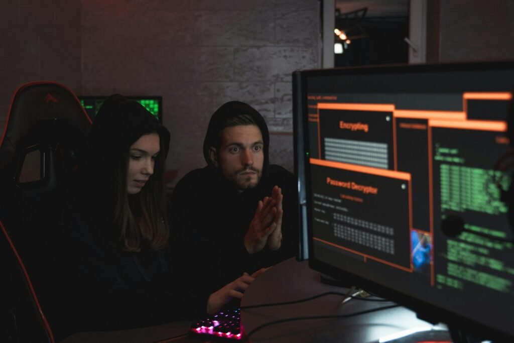 Cybersecurity experts in hoodies analyzing encrypted data on computer screens in an indoor setting.