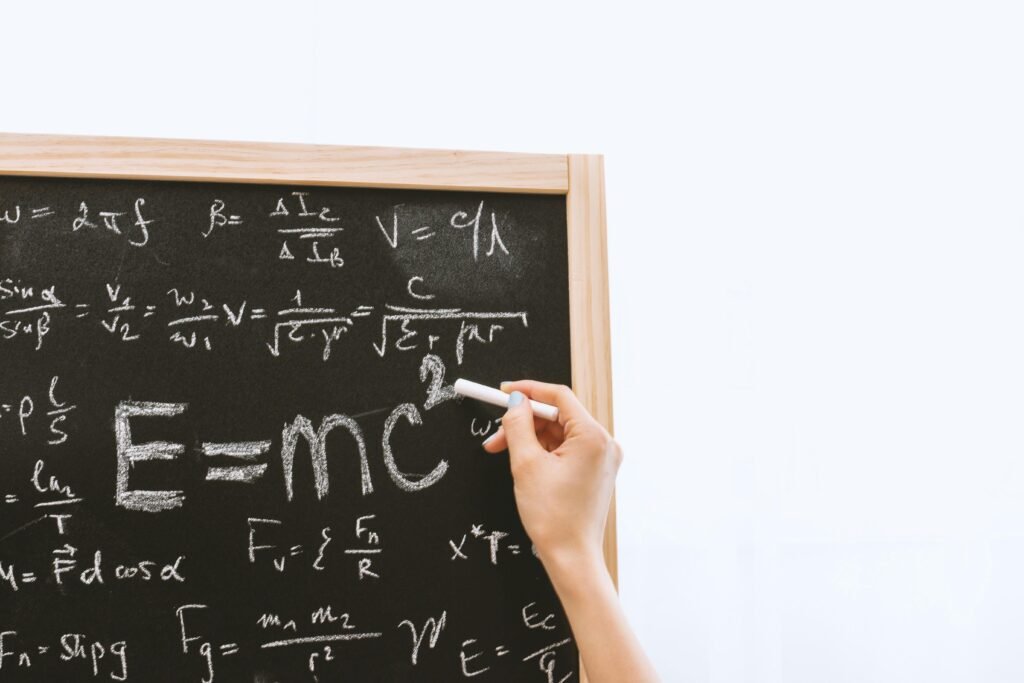 pexels-photo-714699-714699 Close-up of hand writing physics equations on a chalkboard indoors.