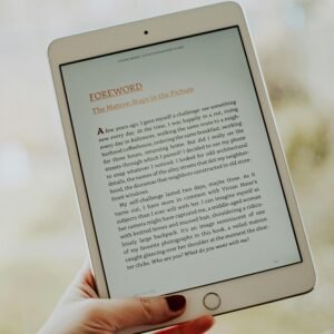 Close-up of a hand holding a tablet displaying an e-book page.